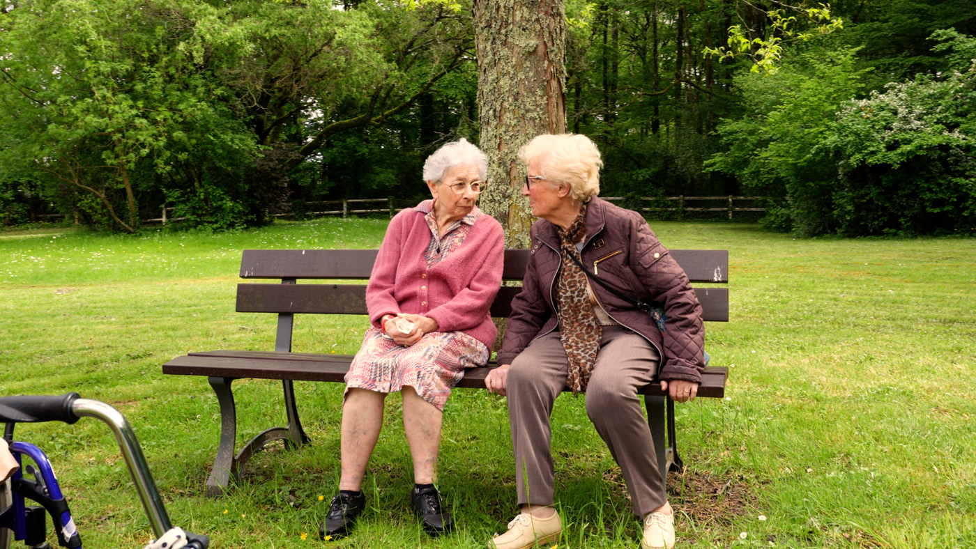 Two elderly women talking on park bench
