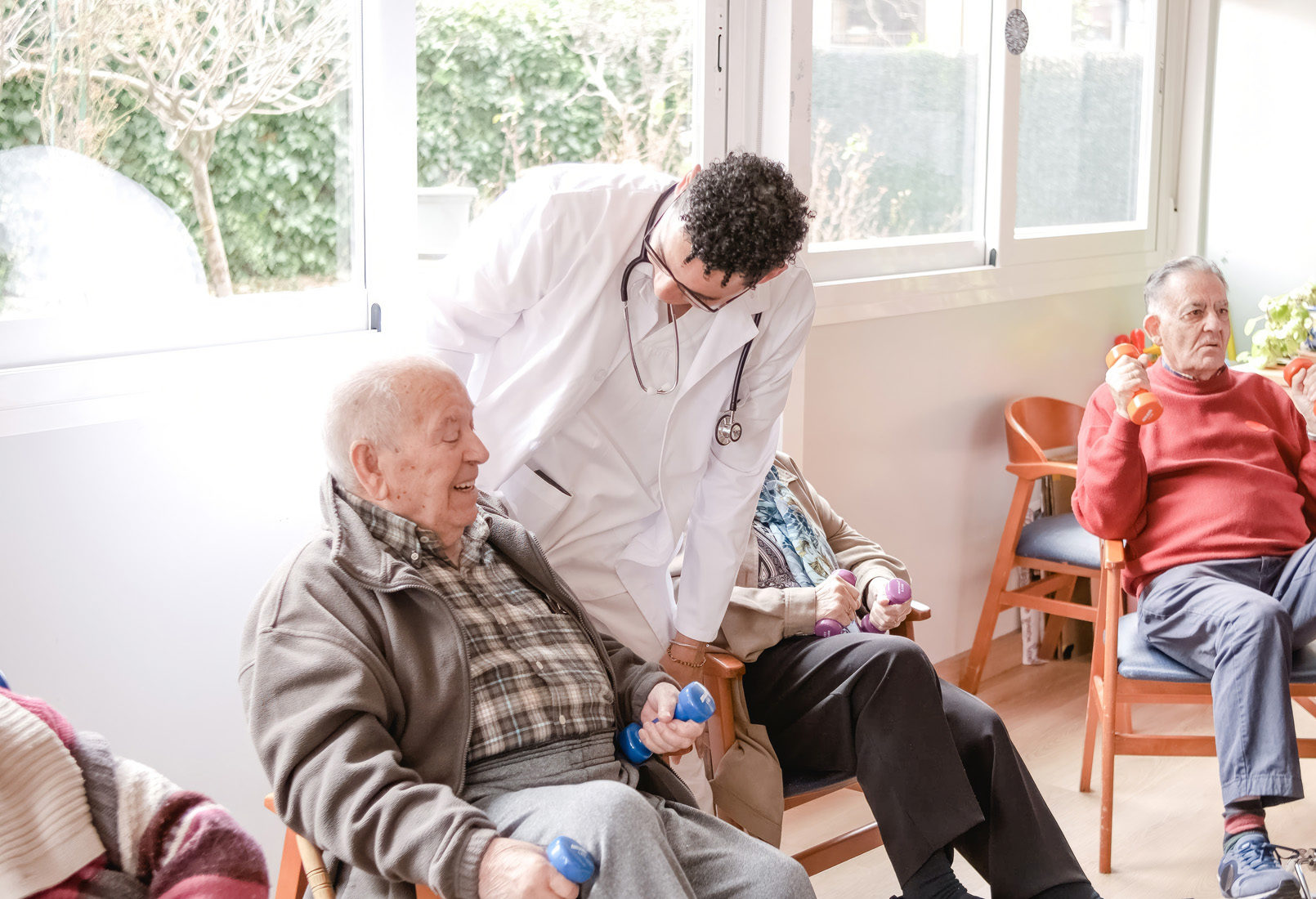 Seniors exercising with dumbbells and doctor assisting
