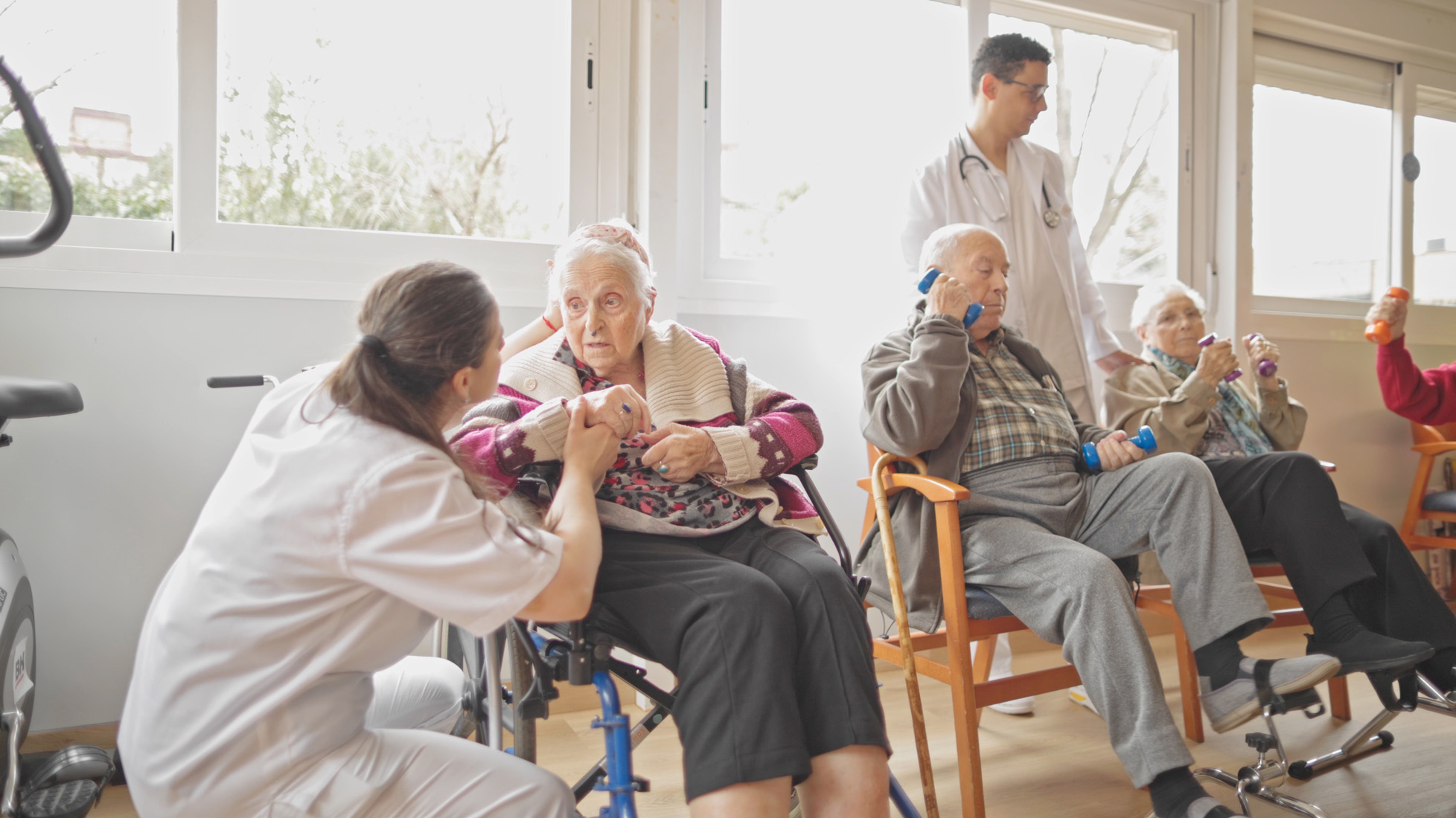 Elderly residents exercising with caregivers in nursing home